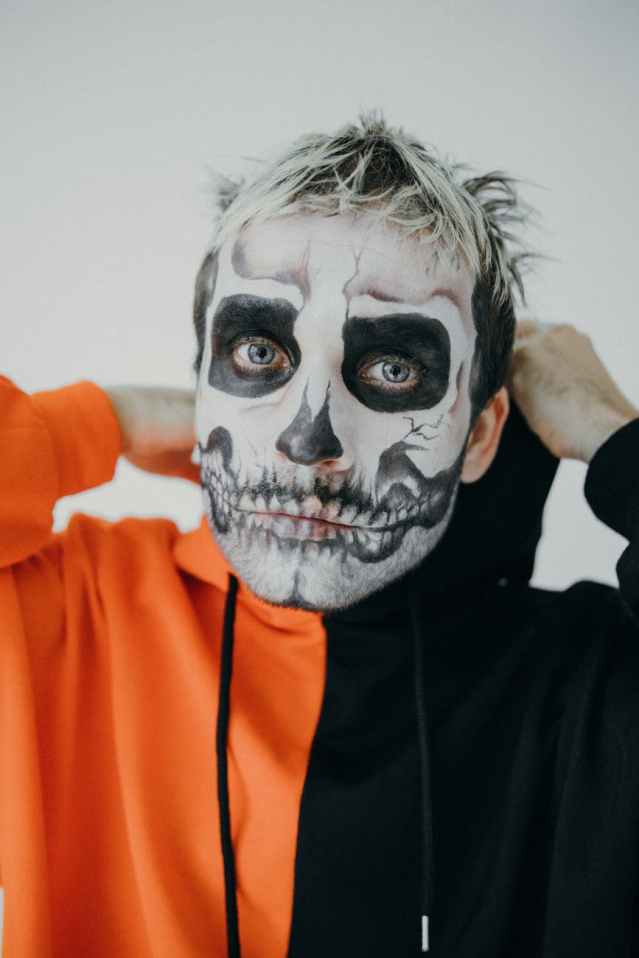 man in orange and black hoodie with halloween face art